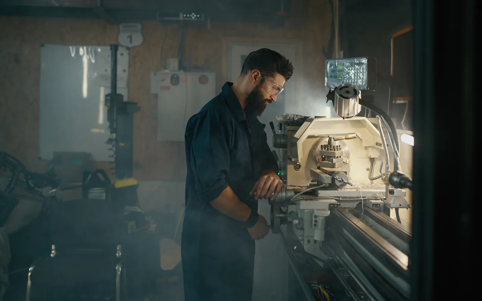 Vakman aan een machine in een donkere werkplaats